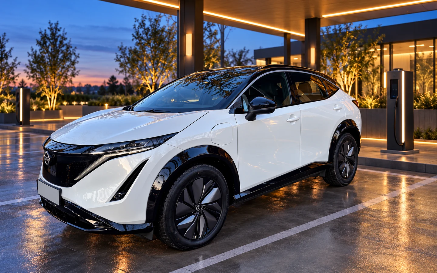 Белый Nissan Ariya у современной зарядной станции вечером